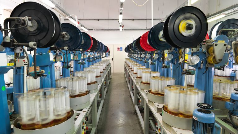 "detail of an indoor industrial production line, in a thread factory"